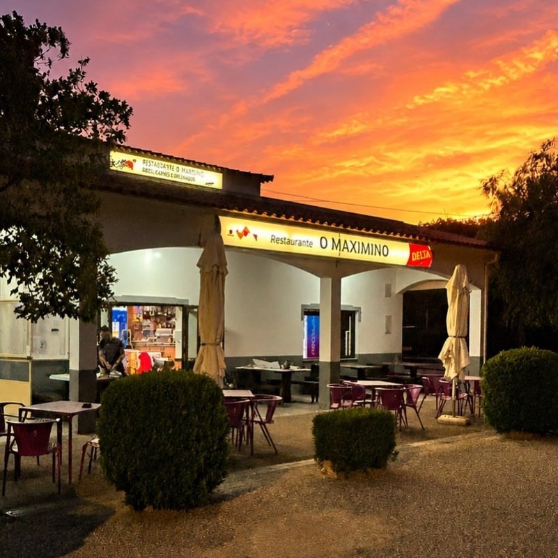 Fachada do Restaurante O Maximino ao fim do dia, com a esplanada, chapéus fechados e o céu alaranjado